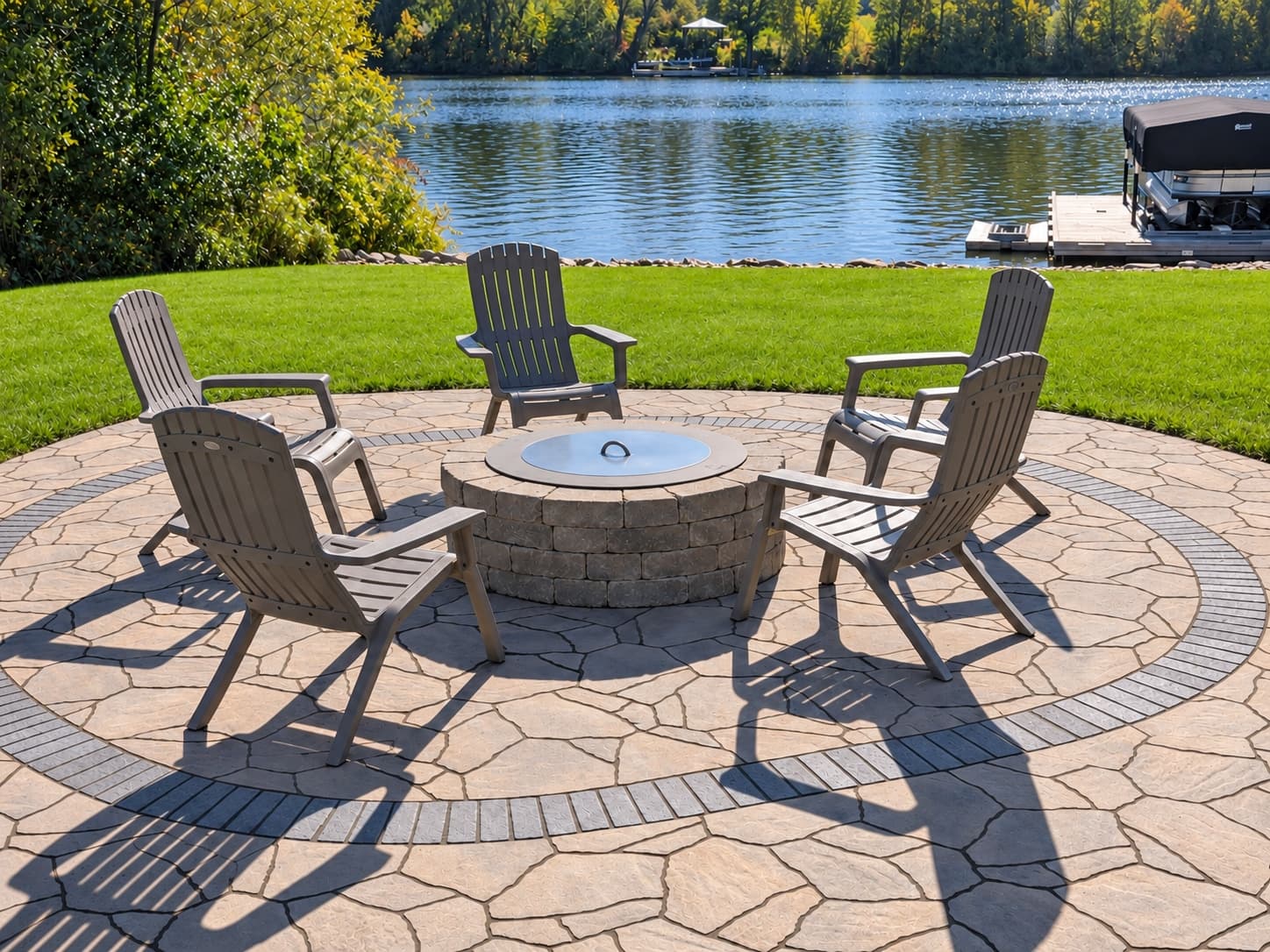 Five Adirondack chairs around a stone fire pit on a circular paver patio overlooking the Fox River.